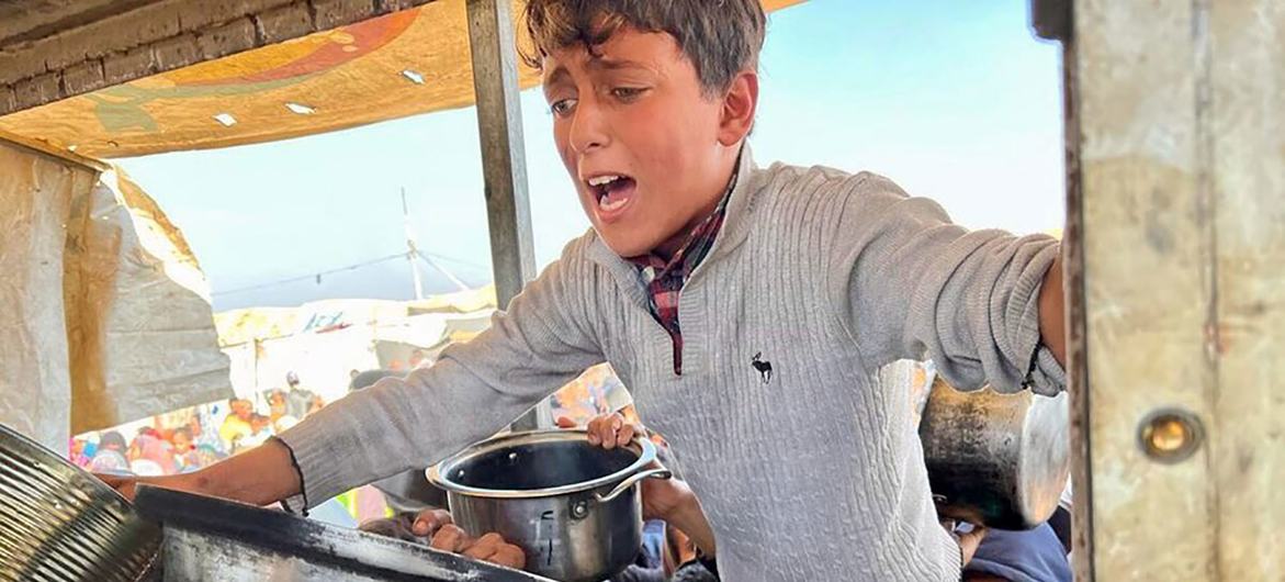 فلسطينيون في خان يونس، جنوب غزة يتجمعون لتلقي مساعدات من برنامج الأغذية العالمي في ظل الانتشار الواسع للجوع وسوء التغذية