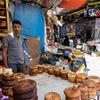 在也门塔伊兹的一个市场上，一名小贩在他的露天面包店里卖东西。