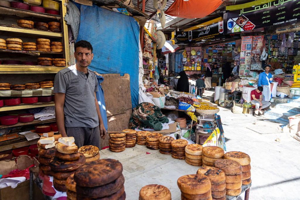 Un hombre yemení se encuentra en un puesto de mercado en Yemen, vendiendo grandes panes planos y redondos.
