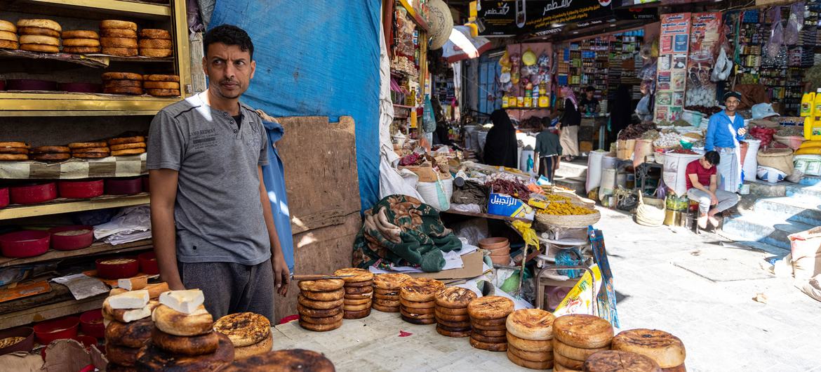 在也门塔伊兹的一个市场上，一名小贩在他的露天面包店里卖东西。