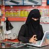A woman mends a laptop at her phone and computer maintenance shop in Taiz, Yemen.