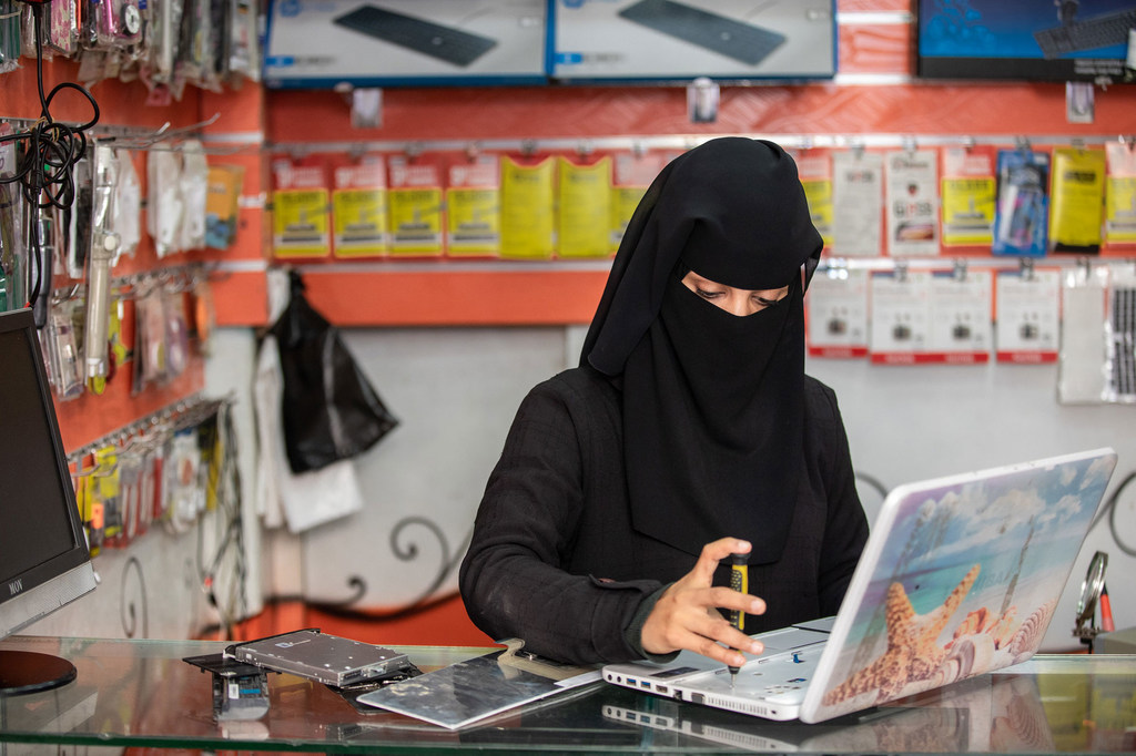 Une femme répare un ordinateur portable dans son atelier de maintenance de téléphones et d'ordinateurs à Taiz, au Yémen.