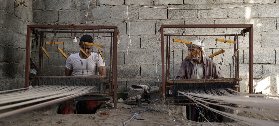 Dois trabalhadores tecem tecidos tradicionais no Iêmen.