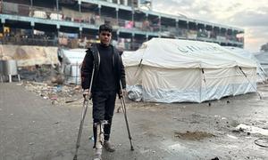 A young man stands closes to temporary shelters in Gaza.