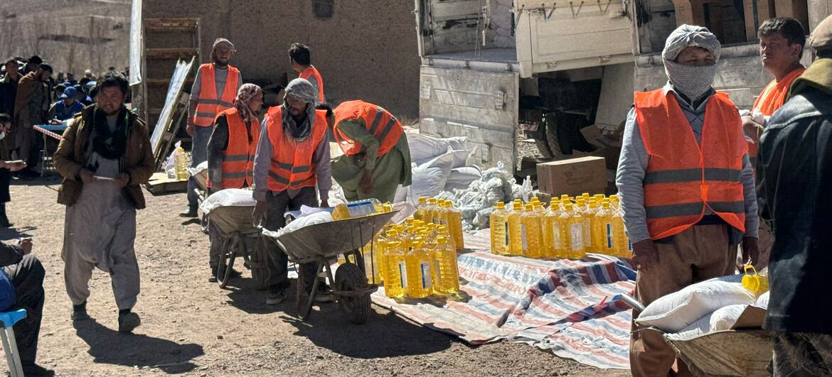 In Parwan Province, Afghanistan, on February 23, 2026, World Food Programme workers in orange vests distribute essential food items including wheat flour, pulses, oil, salt, and LNS to local communities.