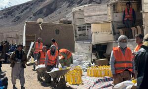 In Parwan Province, Afghanistan, on February 23, 2026, World Food Programme workers in orange vests distribute essential food items including wheat flour, pulses, oil, salt, and LNS to local communities.