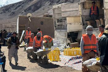 In Parwan Province, Afghanistan, on February 23, 2026, World Food Programme workers in orange vests distribute essential food items including wheat flour, pulses, oil, salt, and LNS to local communities.
