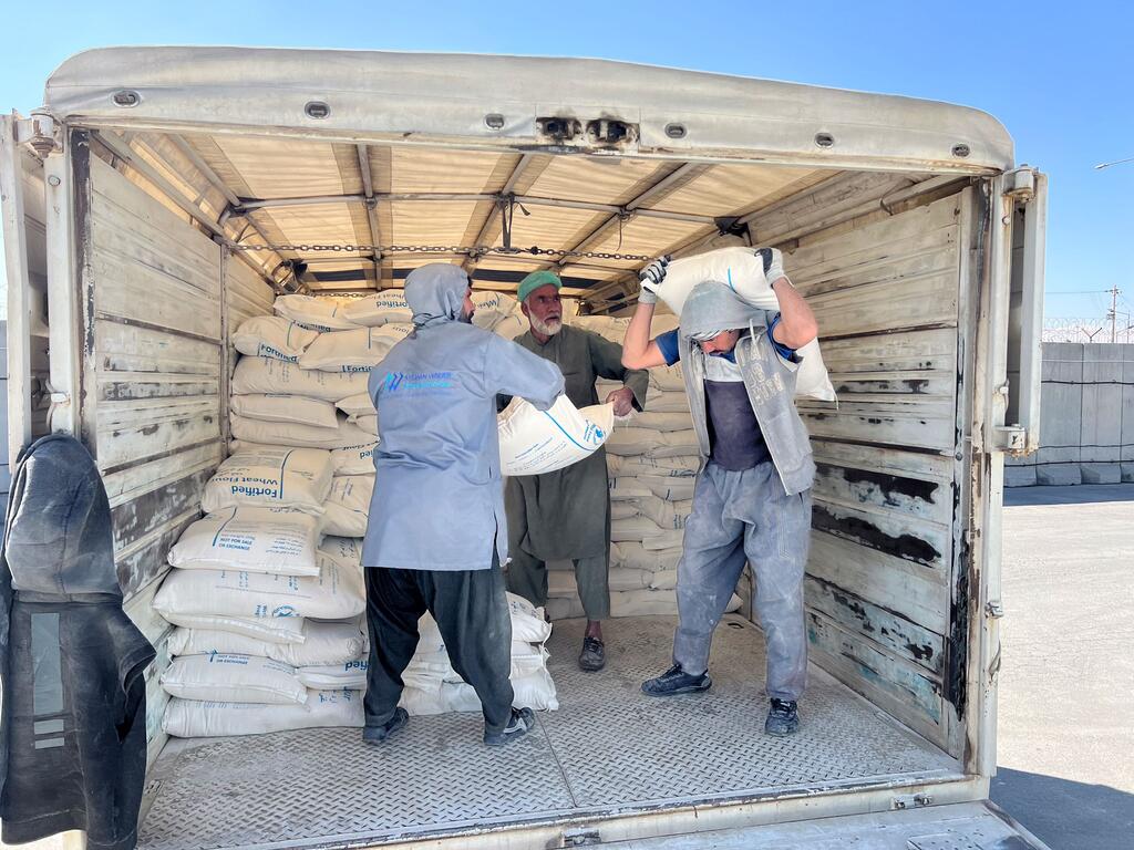 Trabajadores cargan sacos de ayuda alimentaria en un camión en un almacén en Kabul, Afganistán, como parte de un convoy del Programa Mundial de Alimentos que se prepara para distribuir suministros a miles de personas, incluidos los repatriados.