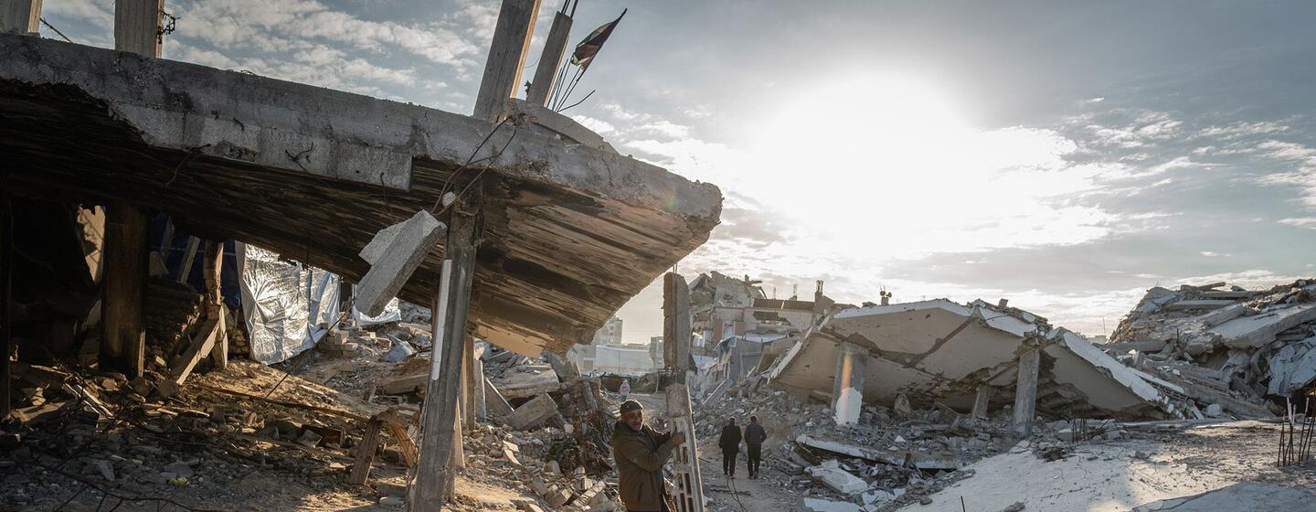 Um homem balança-se de um pedaço pendurado de detritos nas ruínas da casa de seu ex-vizinho em Al-Zarqaa, Cidade de Gaza. A família, deslocada pela guerra e pelas operações terrestres/aéreas, agora vive em uma tenda sobre os escombros e depende da assistência do PAM para sobreviver.