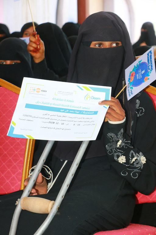 Nabila recevant son certificat pour avoir suivi le cours de formation à l'espace sûr pour les femmes et les filles soutenu par l'UNFPA.