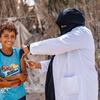 也门的一名卫生工作者在社区宣传活动中为一名小男孩接种疫苗（资料图片）。