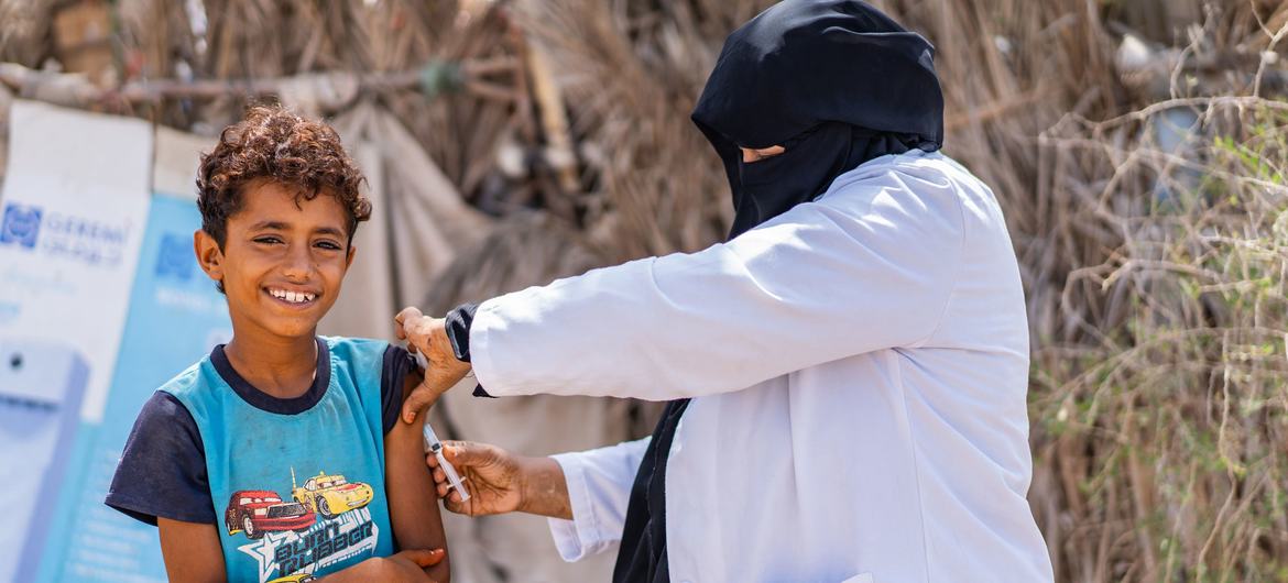也门的一名卫生工作者在社区宣传活动中为一名小男孩接种疫苗（资料图片）。