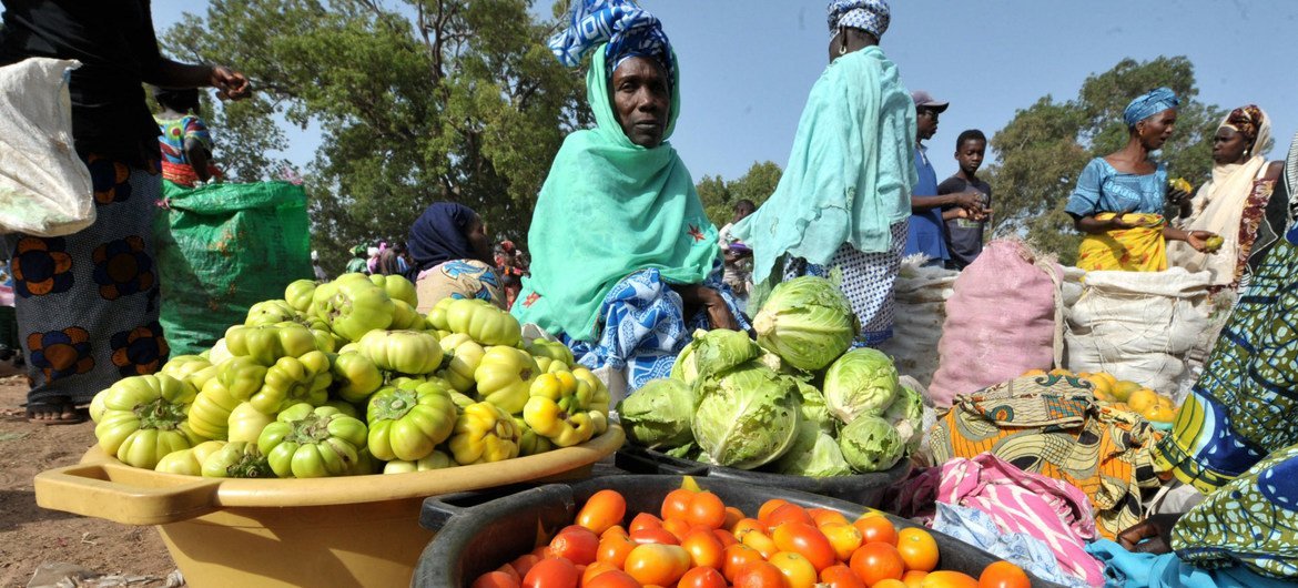 Une femme vend des légumes sur un marché local.