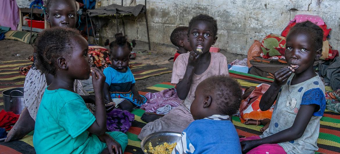 Children who have fled with their families from Sudan eat food provided by WFP at a centre in South Sudan.