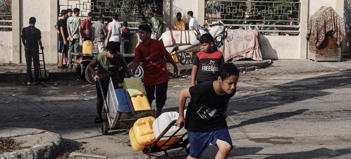 Children collect water in Khan Younis city, in the southern Gaza Strip.