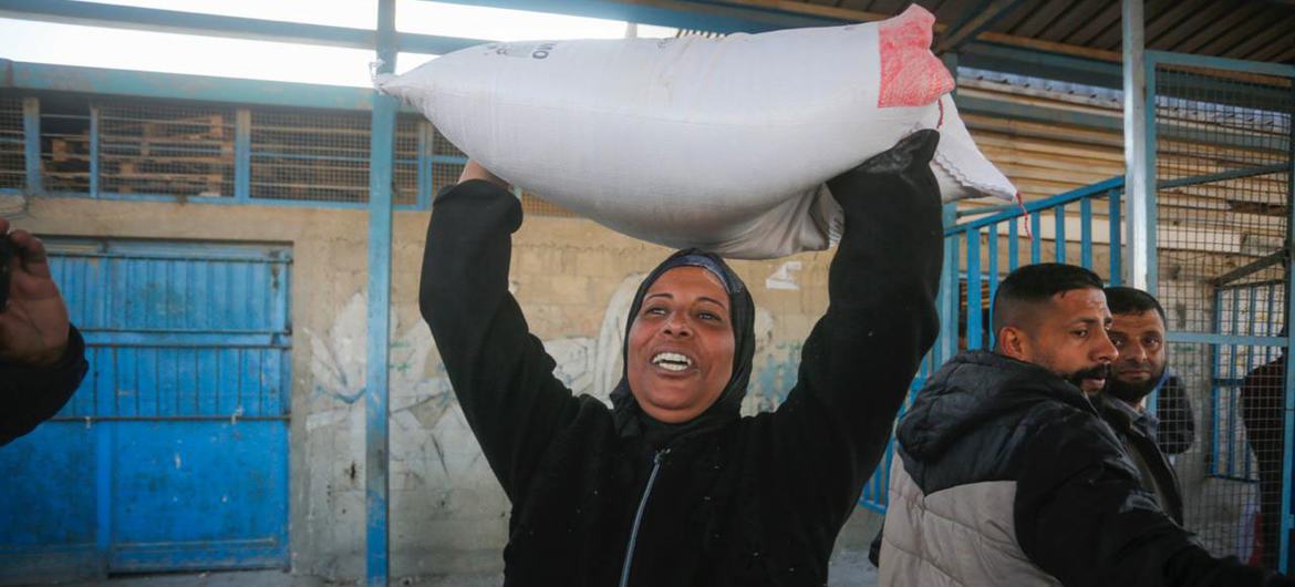 Una mujer lleva harina distribuida por UNRWA en Gaza.