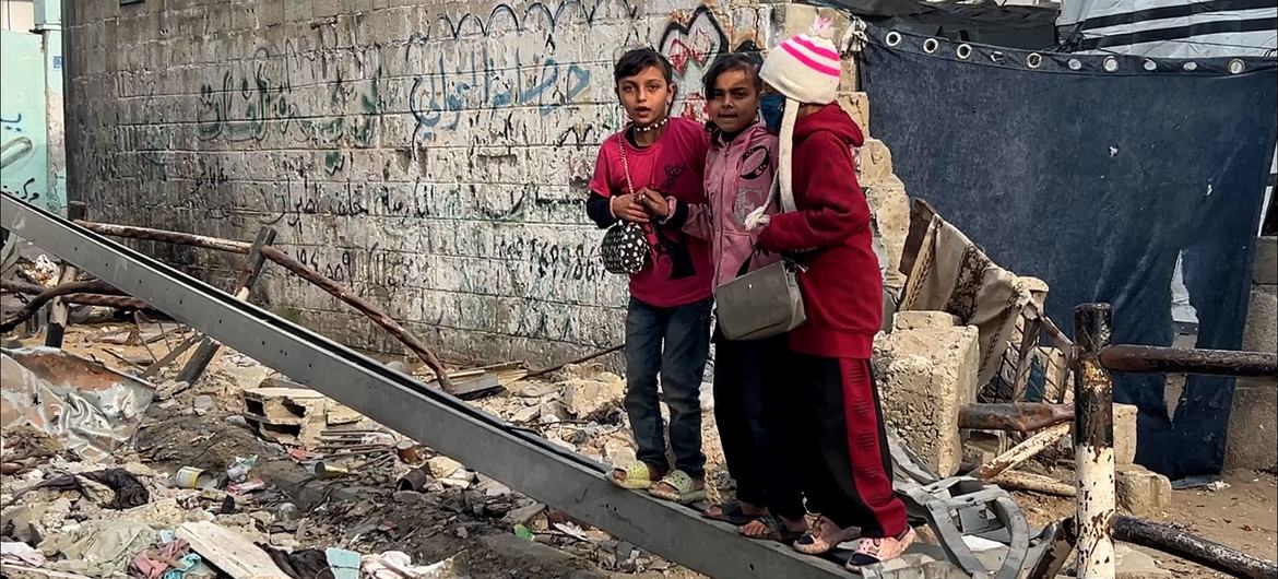 Children in Gaza stand on debris from a destroyed building. 