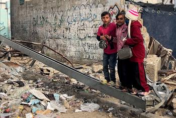 Children in Gaza stand on debris from a destroyed building. 