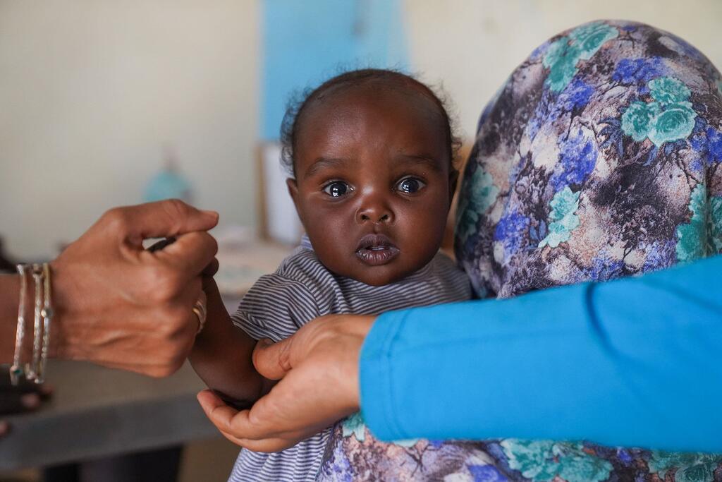 Une mère tient sa fille de sept mois pendant qu'elle est vaccinée dans un centre de santé soutenu par l'UNICEF à Tawila, dans le Darfour du Nord, au Soudan, lors d'une campagne de vaccination contre la rougeole.