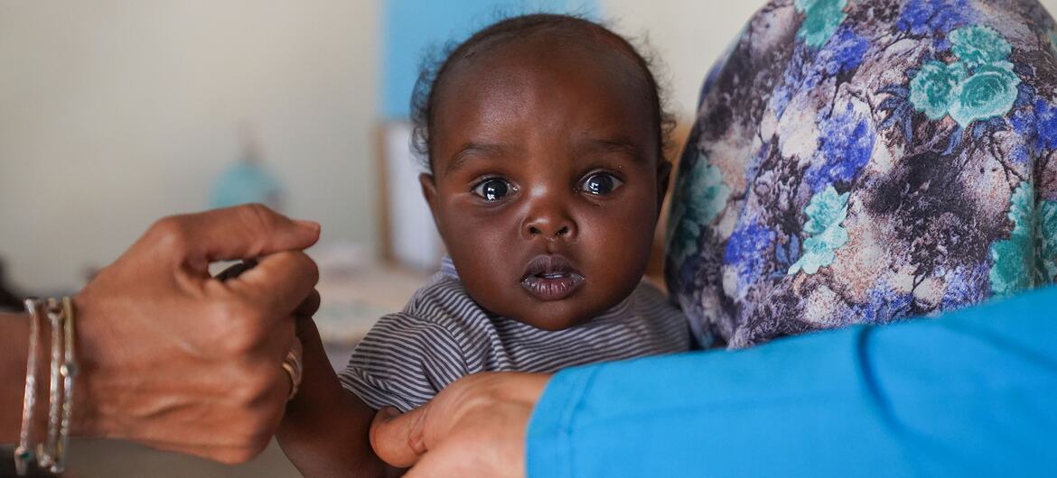Une mère tient sa fille de sept mois pendant qu'elle est vaccinée dans un centre de santé soutenu par l'UNICEF à Tawila, dans le Darfour du Nord, au Soudan, lors d'une campagne de vaccination contre la rougeole.