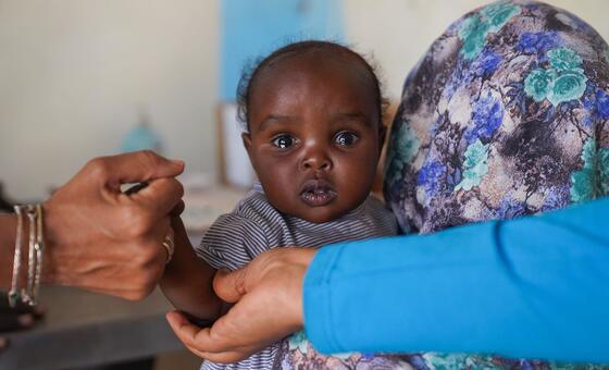 طفلة تبلغ من العمر سبعة أشهر مع أمها، تحصل على التطعيم ضد الحصبة في منشأة صحية تدعمها اليونيسيف في مدينة طويلة، بولاية شمال دارفور. 