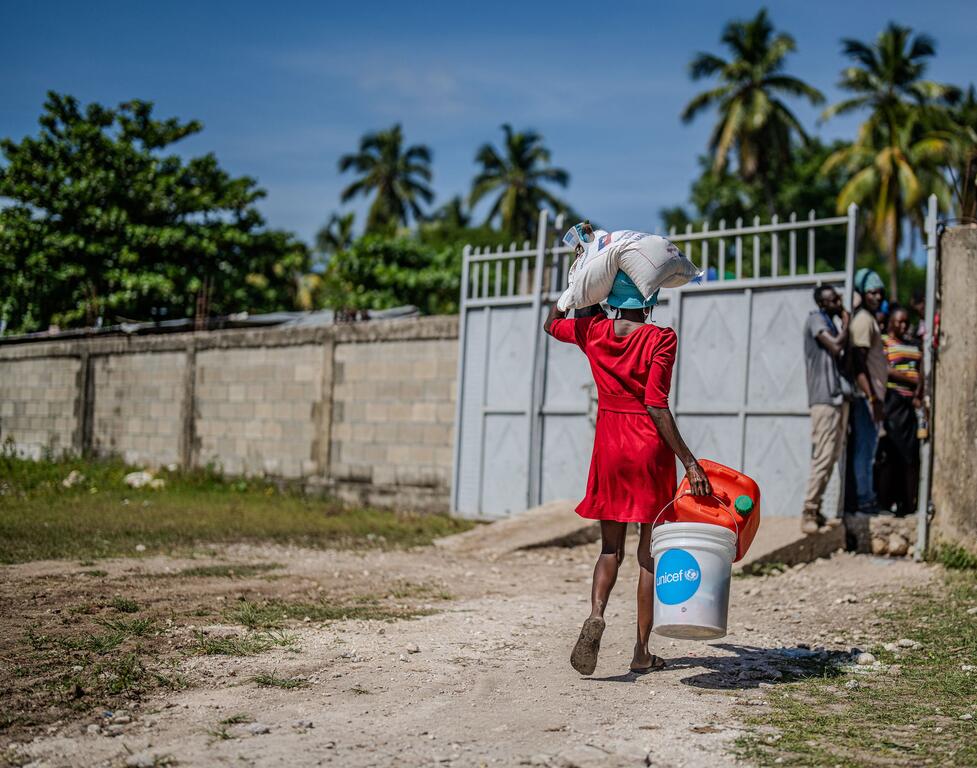 Une femme en Haïti se rend sur un site de distribution alimentaire.