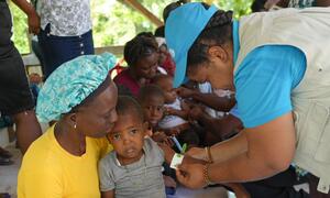 A UNICEF health worker administers medical care to a child held by his mother at a mobile clinic in Boucan Carré, Haiti, serving displaced families affected by violence.
