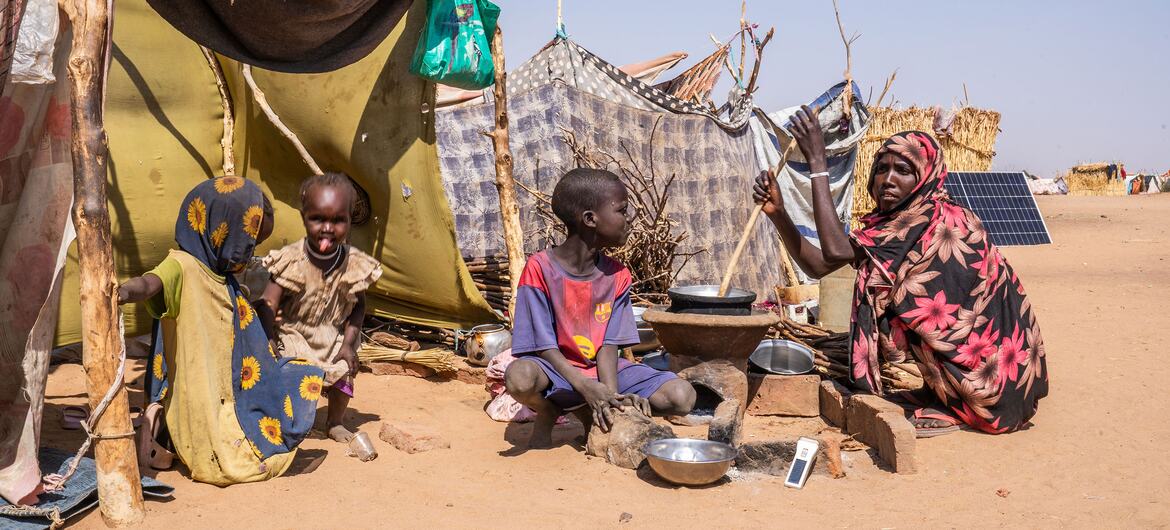 A woman prepares food for her children in a makeshift camp in Tawila, North Darfur, Sudan, where displaced families have sought refuge due to ongoing conflict.