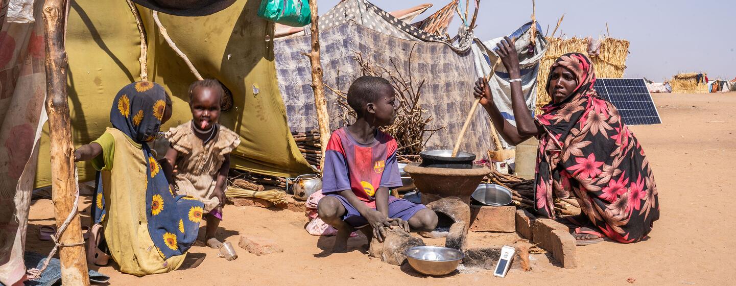 Une femme prépare de la nourriture pour ses enfants dans un camp improvisé à Tawila, dans le Darfour du Nord, au Soudan, où des familles déplacées ont cherché refuge en raison du conflit en cours.