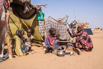 A woman prepares food for her children in a makeshift camp in Tawila, North Darfur, Sudan, where displaced families have sought refuge due to ongoing conflict.