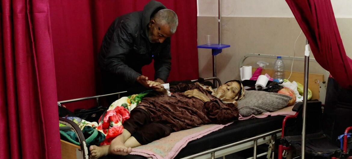 Un patient âgé atteint d'un cancer est allongé dans un lit d'hôpital à Gaza, assisté par un soignant.