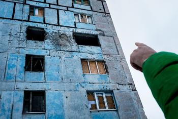 Uma criança aponta para danos em sua antiga casa em Donetsk Oblast, Ucrânia