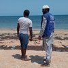 موظف في المنظمة الدولية للهجرة في جيبوتي يتحدث مع مهاجر وصل إلى الدولة الأفريقية على متن قارب.