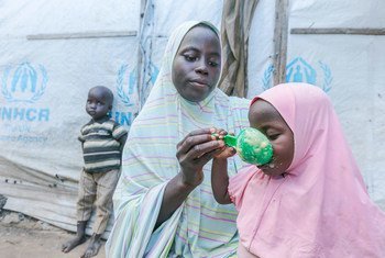 尼日利亚的一位母亲用从世界粮食计划署分发点领取的谷类食品为她的孩子准备食物。