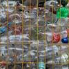 Une cage métallique remplie de diverses bouteilles en plastique, notamment des contenants de Coca-Cola et d'eau minérale, dans un centre de recyclage.