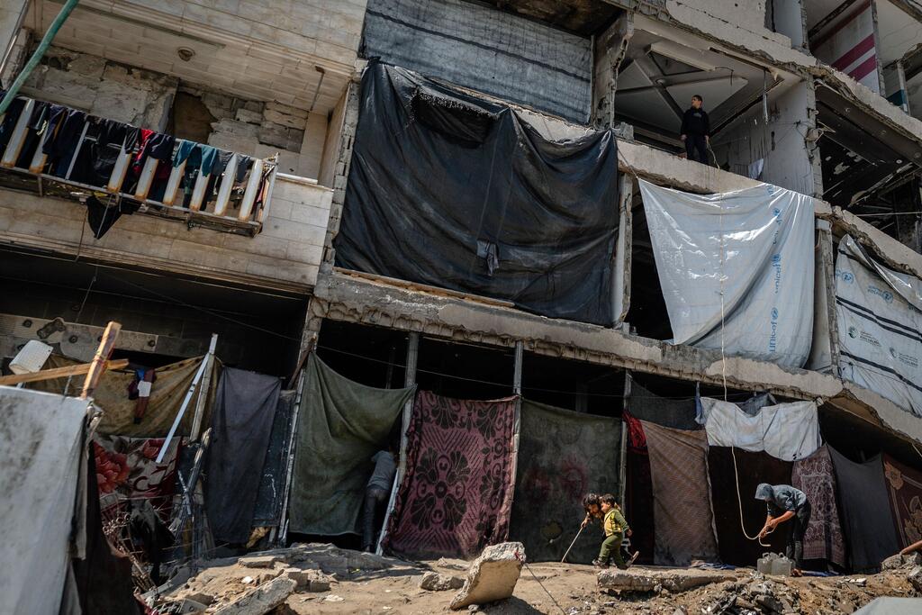 Un bâtiment endommagé à Gaza City avec des abris improvisés en bâches et en tissu installés dans les fenêtres et sur les balcons du rez-de-chaussée.