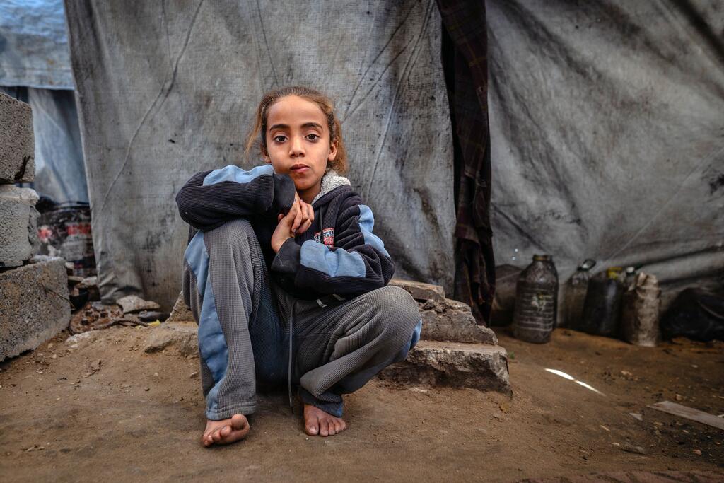طفلة فلسطينية تبلغ من العمر 8 سنوات، تجلس خارج خيمة في مأوى مؤقت للنازحين في مدينة غزة حيث تعيش عائلتها.