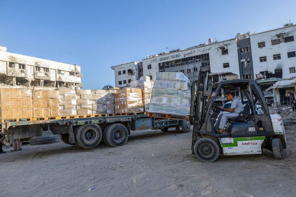 Mwendeshaji wa forklift anapakia masanduku ya vifaa vya matibabu kwenye lori mbele ya majengo yaliyoharibiwa huko Gaza.