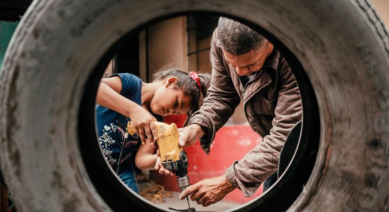 أب وابنته هاجرا من فنزويلا  إلى الإكوادور يقومان بصنع كرسي من إطارات السيارات المستعملة في فناء منزلهما الخلفي.