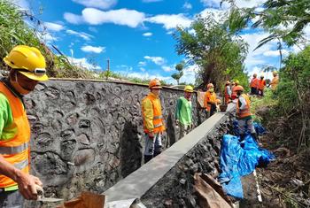 Workers in Indonesia build a wall as a flood prevention measure.