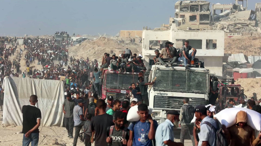 Thousands of people seek aid delivered across the Israeli Zikim border point in northern Gaza.