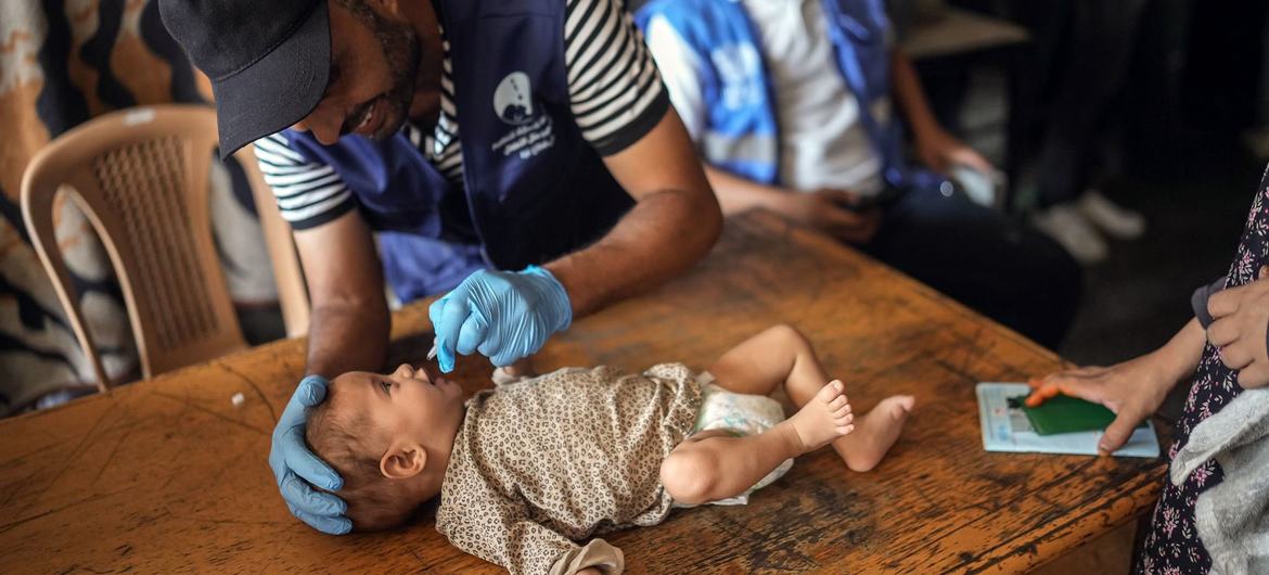 A health worker administers the polio vaccine to a baby in Gaza.