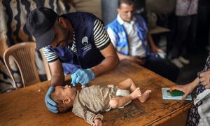 A health worker administers the polio vaccine to a baby in Gaza.