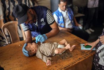 A health worker administers the polio vaccine to a baby in Gaza.