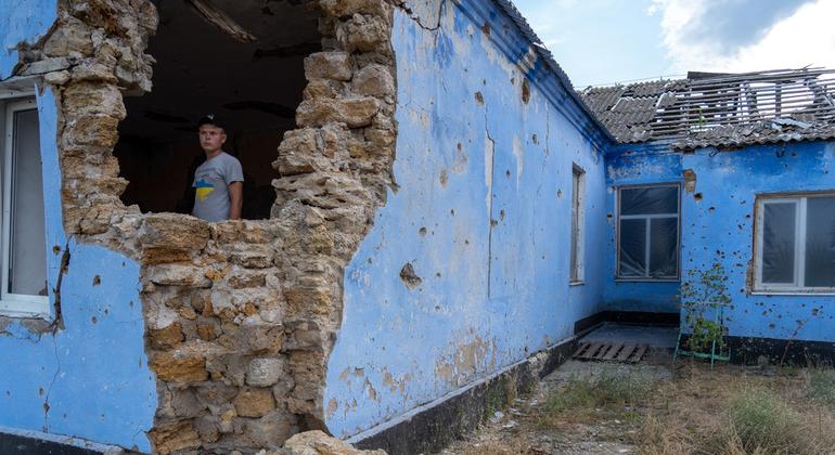 यूक्रेन में हमले के दौरान ध्वस्त हुई स्कूल की इमारत के भीतर खड़ा एक लड़का.