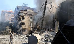 A woman walks past a destroyed building in the southern suburbs of Beirut, the Lebanese capital.