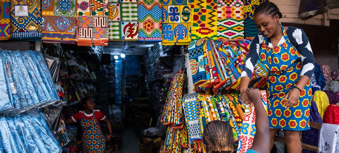 A shopkeeper sells African print fabrics at a market in Ghana. A shopkeeper sells African print fabrics at a market in Ghana.