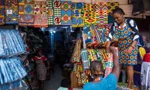 A shopkeeper sells African print fabrics at a  market in Ghana.