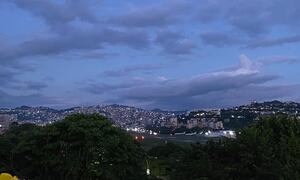 A twilight view of Caracas, Venezuela, showcasing the city's illuminated skyline, surrounding hills, and an airport runway in the foreground.