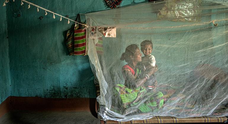 Uma mulher e uma criança sentam-se sob um mosquiteiro em Chhattisgarh, Índia